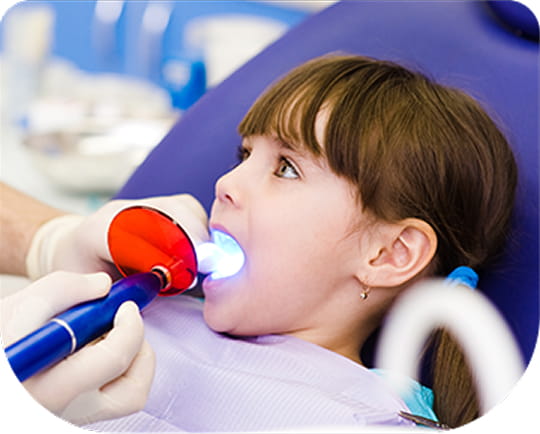 Pediatric dentist using modern dental tools for a child's tooth treatment in Santa Ana